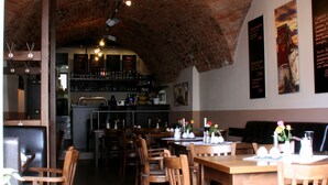 A restaurant with brick ceiling, wooden tables and chairs, and a bar area in the background. - Hotel Zittauer Hof (Zittau)