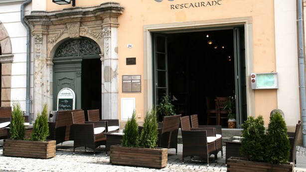An outdoor seating area with wicker chairs and planters, in front of a building with the sign "ESSBAR RESTAURANT". - Hotel Zittauer Hof (Zittau)