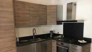 A modern kitchen with stainless steel appliances, wooden cabinets, and a black countertop. - Vicolo del Geppone (Lucca)
