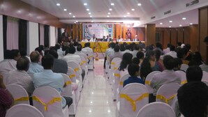 Une salle de conférence avec des rangées de chaises disposées face à une scène.