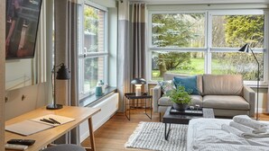 A modern living room with a sofa, a desk, and a TV. - Ferienhäuser & Appartments Düneneck 6 (St. Peter-Ording)