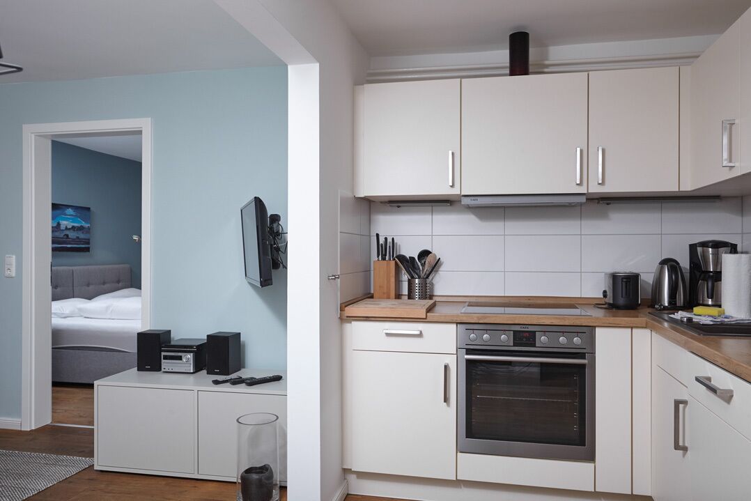 Una cucina compatta con mobili bianchi, un fornello e una macchina da caffè.