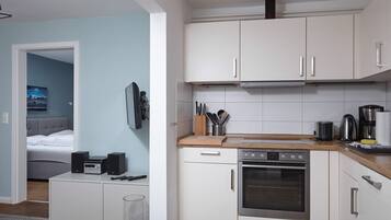 Una cucina compatta con mobili bianchi, un fornello e una macchina da caffè.
