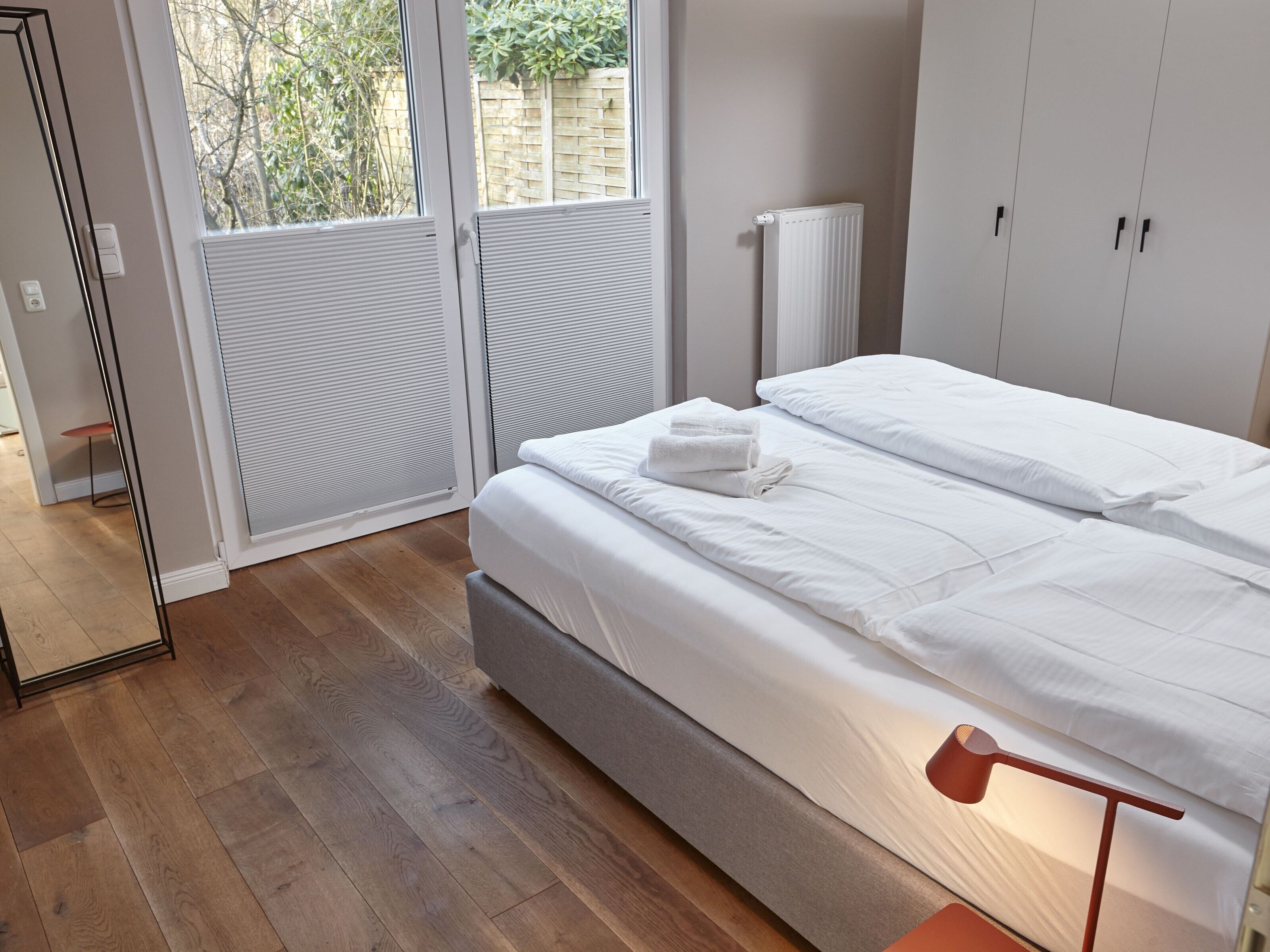 A bedroom with a bed, a radiator, and a window with blinds.