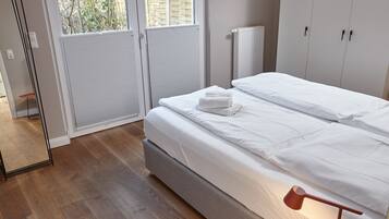 A bedroom with a bed, a radiator, and a window with blinds.