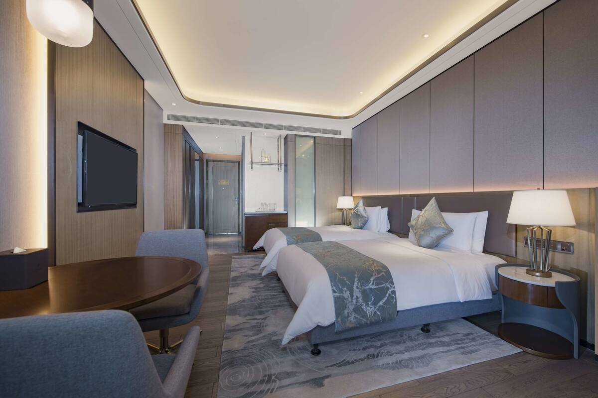 Une chambre d’hôtel moderne avec un grand lit, deux tables de chevet, un bureau et une télévision.