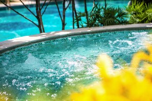 Een hottub met helder water en bubbels, omringd door groen.
