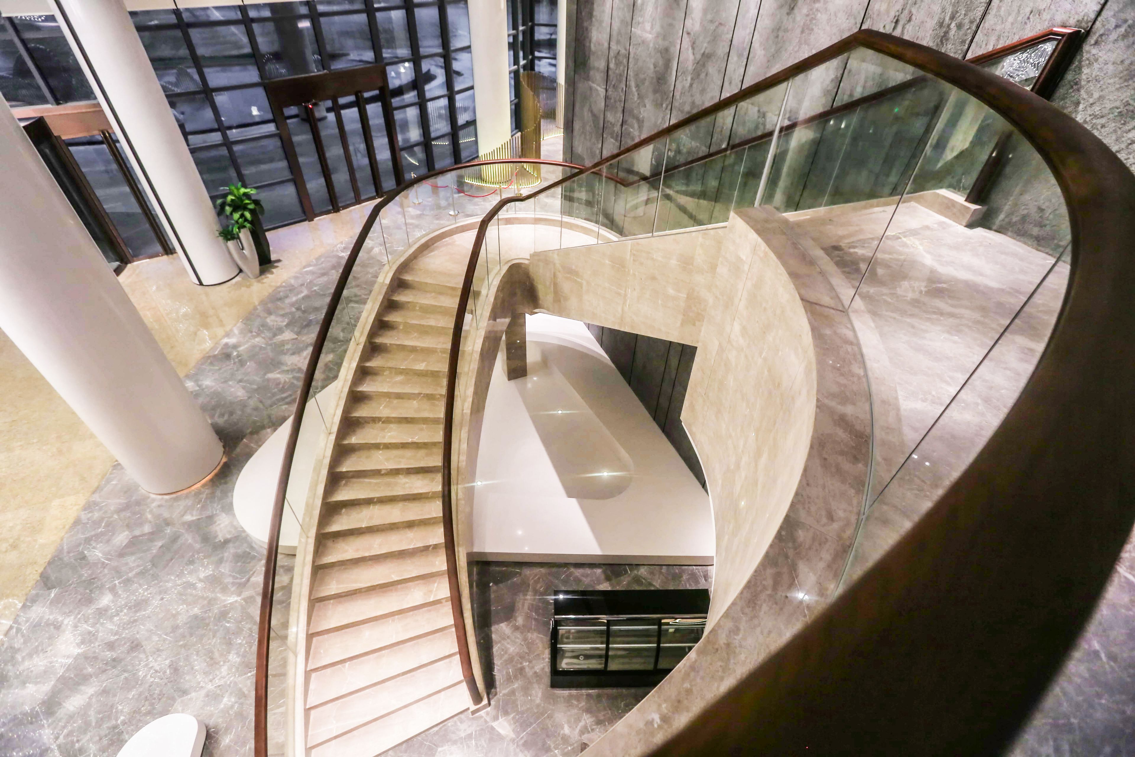 A modern spiral staircase with glass railings and a white interior.