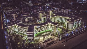 Un moderno complejo hotelero con varias edificaciones interconectadas, un patio central y un área de estacionamiento.