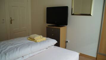 Ein Hotelzimmer mit einem Bett, einem Fernseher auf einer Holzkommode und einem Spiegel an der Wand.