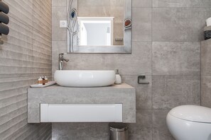 A modern bathroom with a large sink, mirror, and toilet.