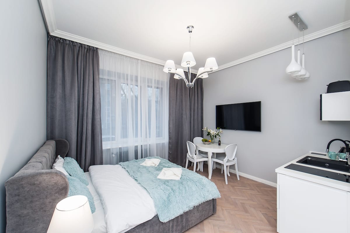 A modern bedroom with a bed, a desk, and a TV.