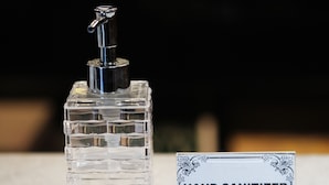 A hand sanitizer bottle with a pump dispenser and a sign labeled "HAND SANITIZER". - DE Apartment (Pattaya)