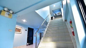 A staircase with metal railings and a tiled floor, leading to an upper level. - DE Apartment (Pattaya)
