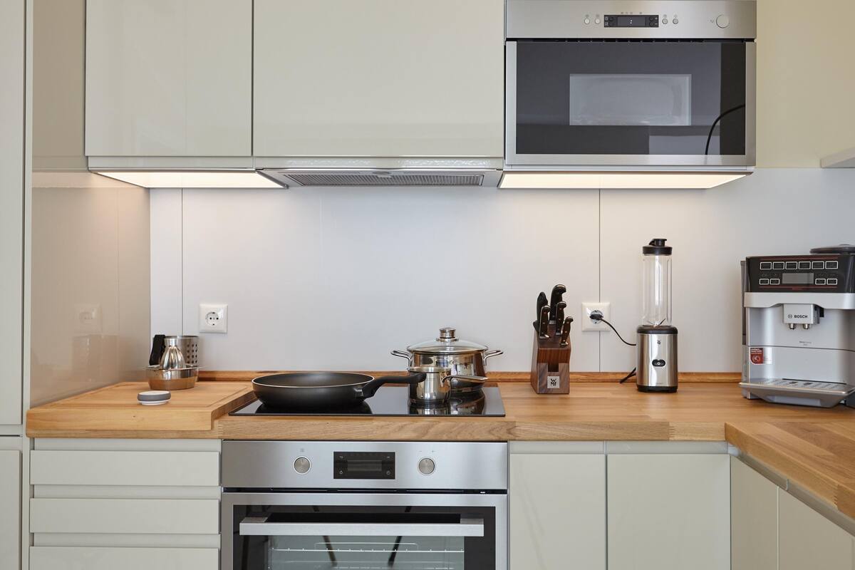 Eine moderne Küche mit Edelstahlgeräten, darunter ein Backofen, eine Mikrowelle und eine Bosch Kaffeemaschine.