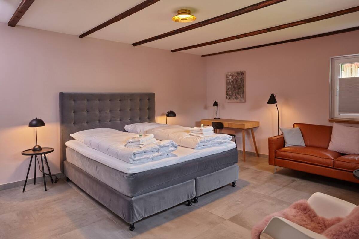Ein Schlafzimmer mit einem großen Bett, einem Schreibtisch, einem Sessel und einem Sofa.