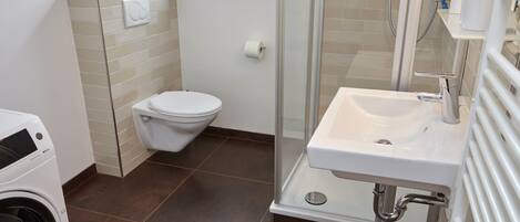 Une salle de bain moderne équipée de toilettes, d’une douche et d’un lavabo.