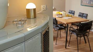 Una cocina con estufa antigua, una lámpara moderna y un comedor con mesa de madera y sillas negras.