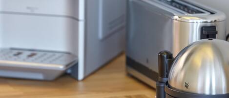 A kitchen with a coffee maker, toaster, and a kettle on a wooden floor.