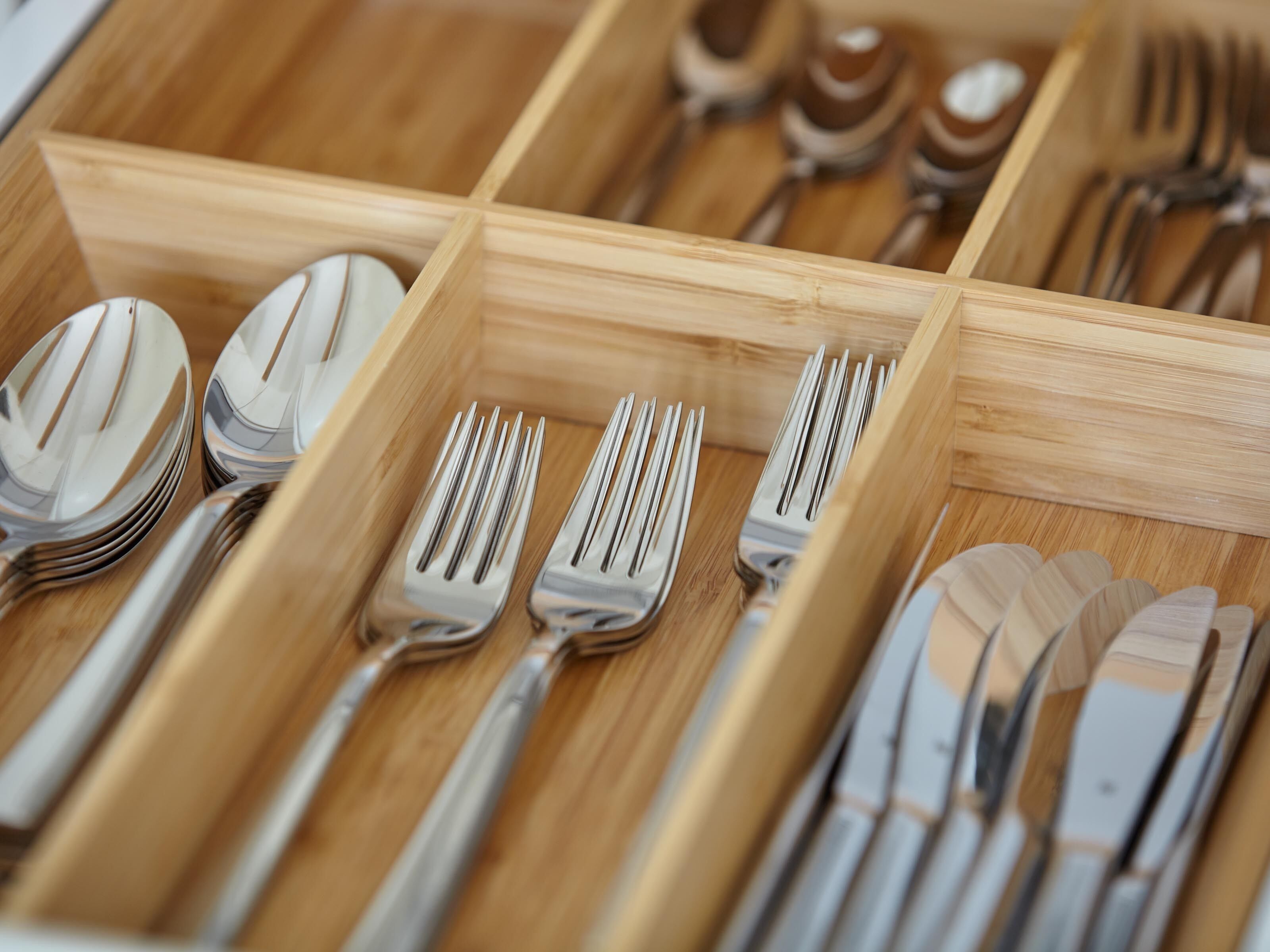 A drawer with neatly organized cutlery including forks, spoons, and knives.