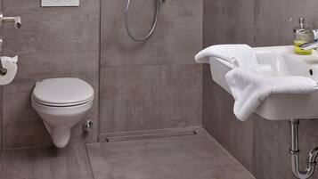 A modern bathroom with a toilet, shower, and sink.