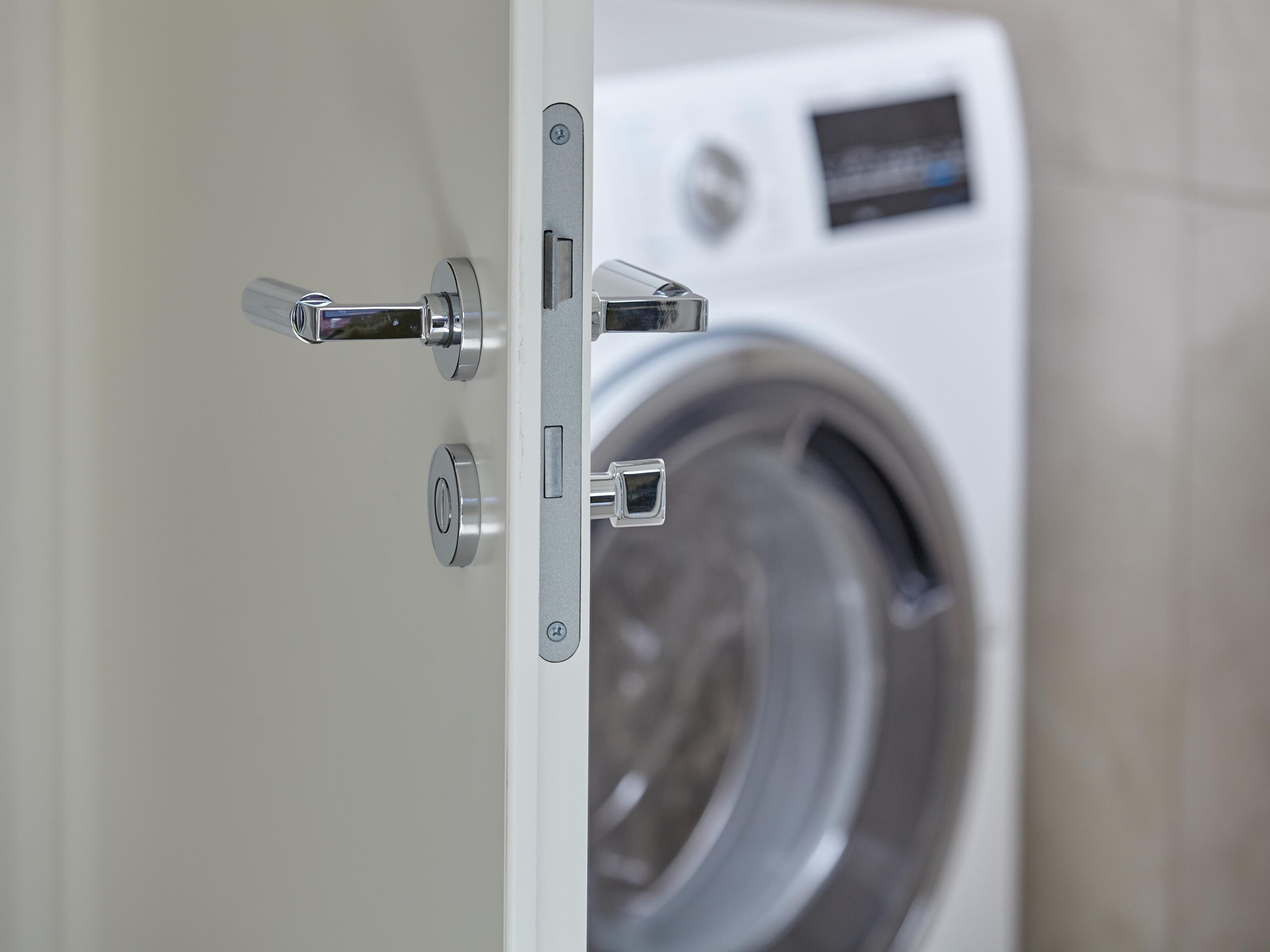 Vue de face d’un lave-linge doté d’une poignée de porte métallique et d’un panneau de commande.