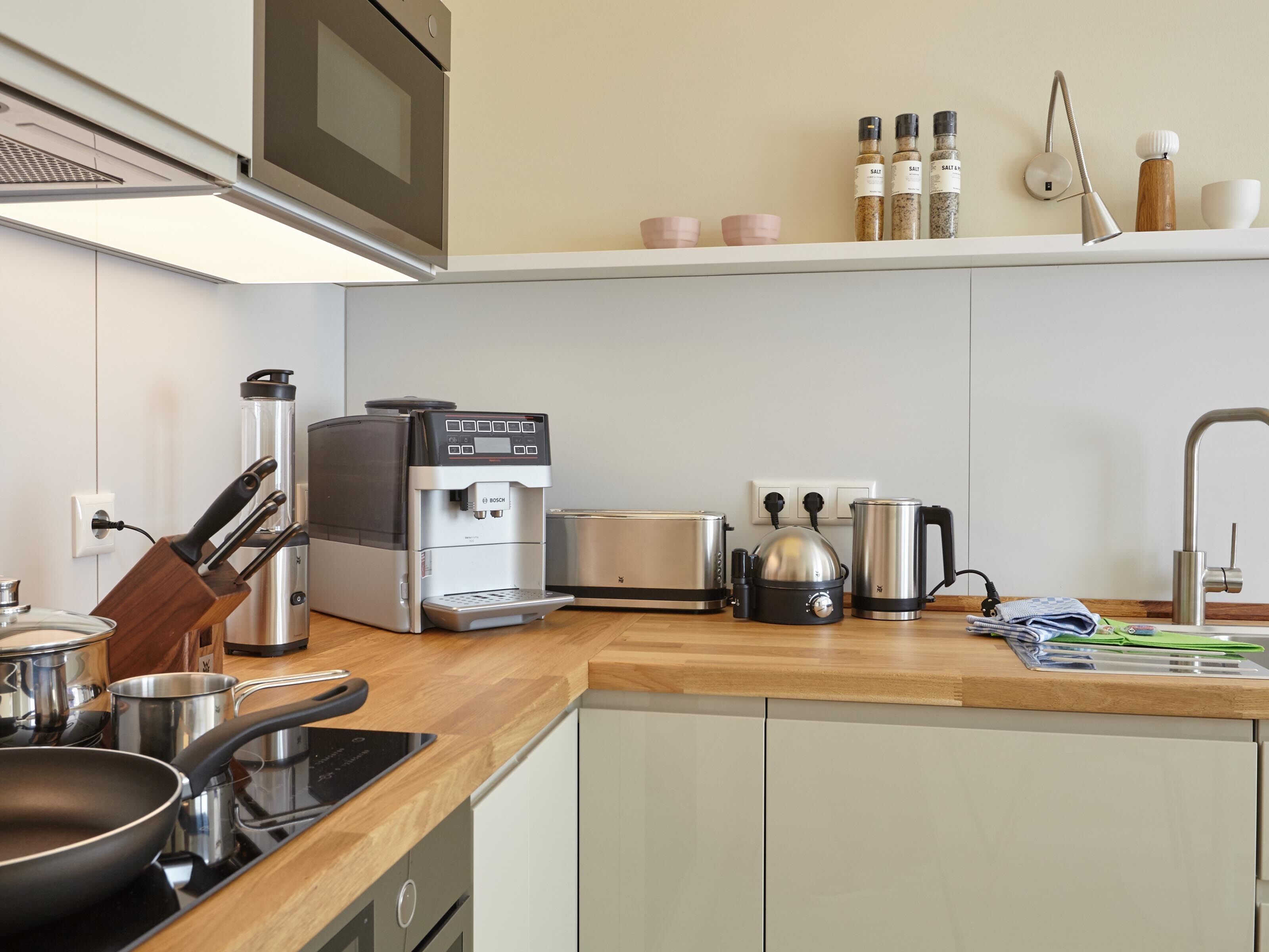 A modern kitchen with a Bosch coffee machine, a toaster, a kettle, and a stove.
