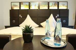 A hotel room with a bed, a bedside table with a potted plant, and two bottles of water on a tray. - Hotel Restaurant Pfeffermühle (Balingen)