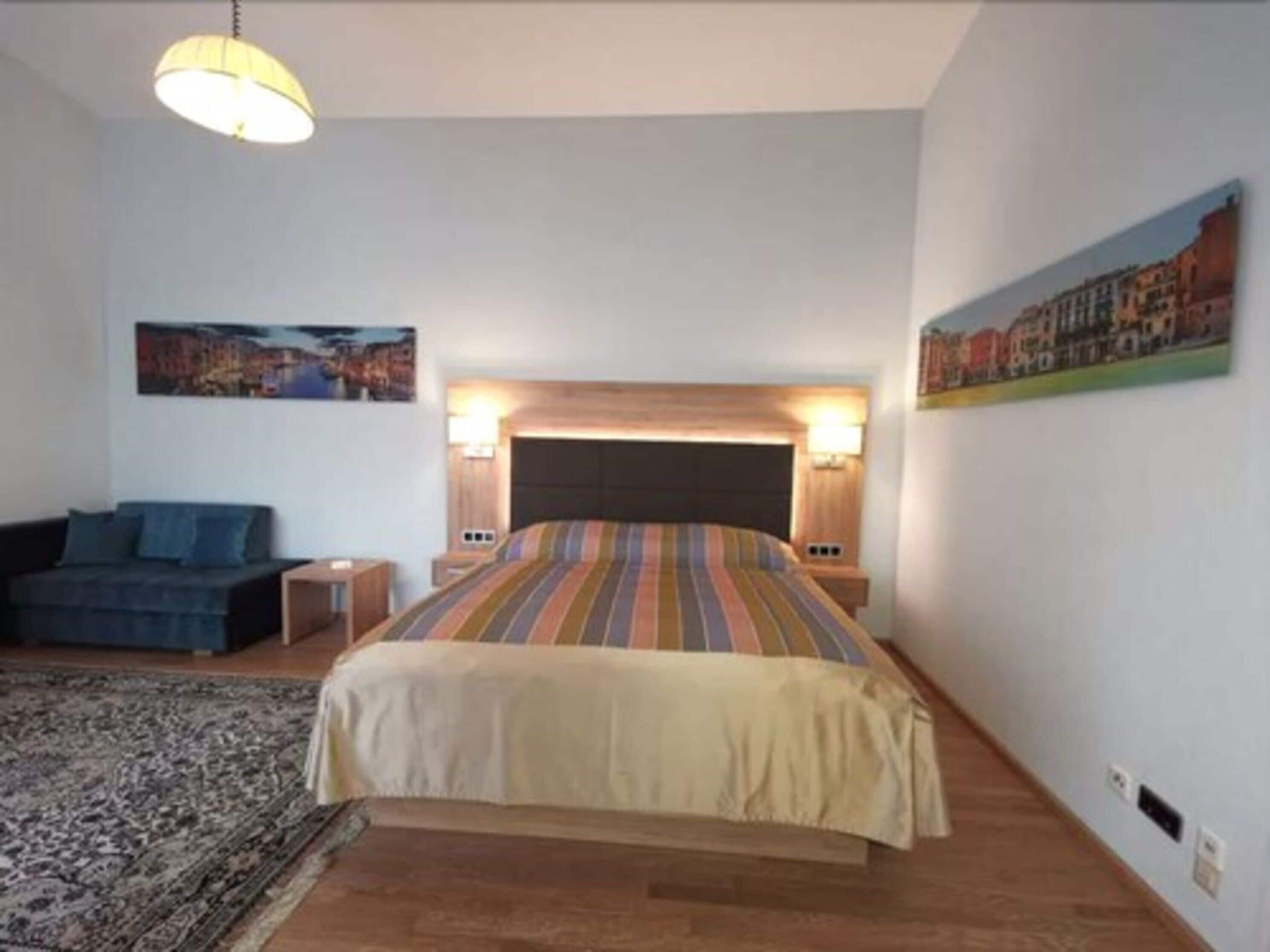 Ein Schlafzimmer mit einem großen Bett, einem Sofa, einem Teppich und zwei Wandlampen.