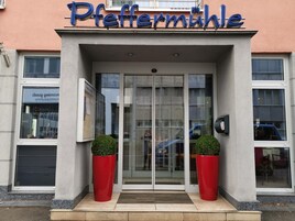La entrada de un edificio con puerta de vidrio y un letrero que dice 'Pfeffermühle'.