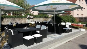 An outdoor seating area with tables and chairs, umbrellas, and a stone wall. - Hotel Restaurant Pfeffermühle (Balingen)