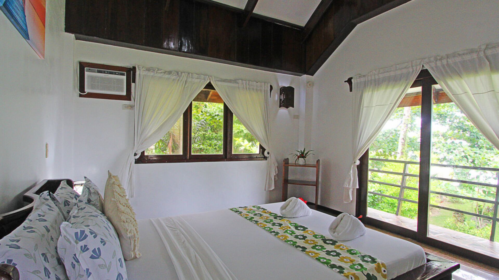 A bedroom with a bed, a desk, and a window with curtains.