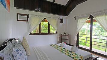 A bedroom with a bed, a desk, and a window with curtains.
