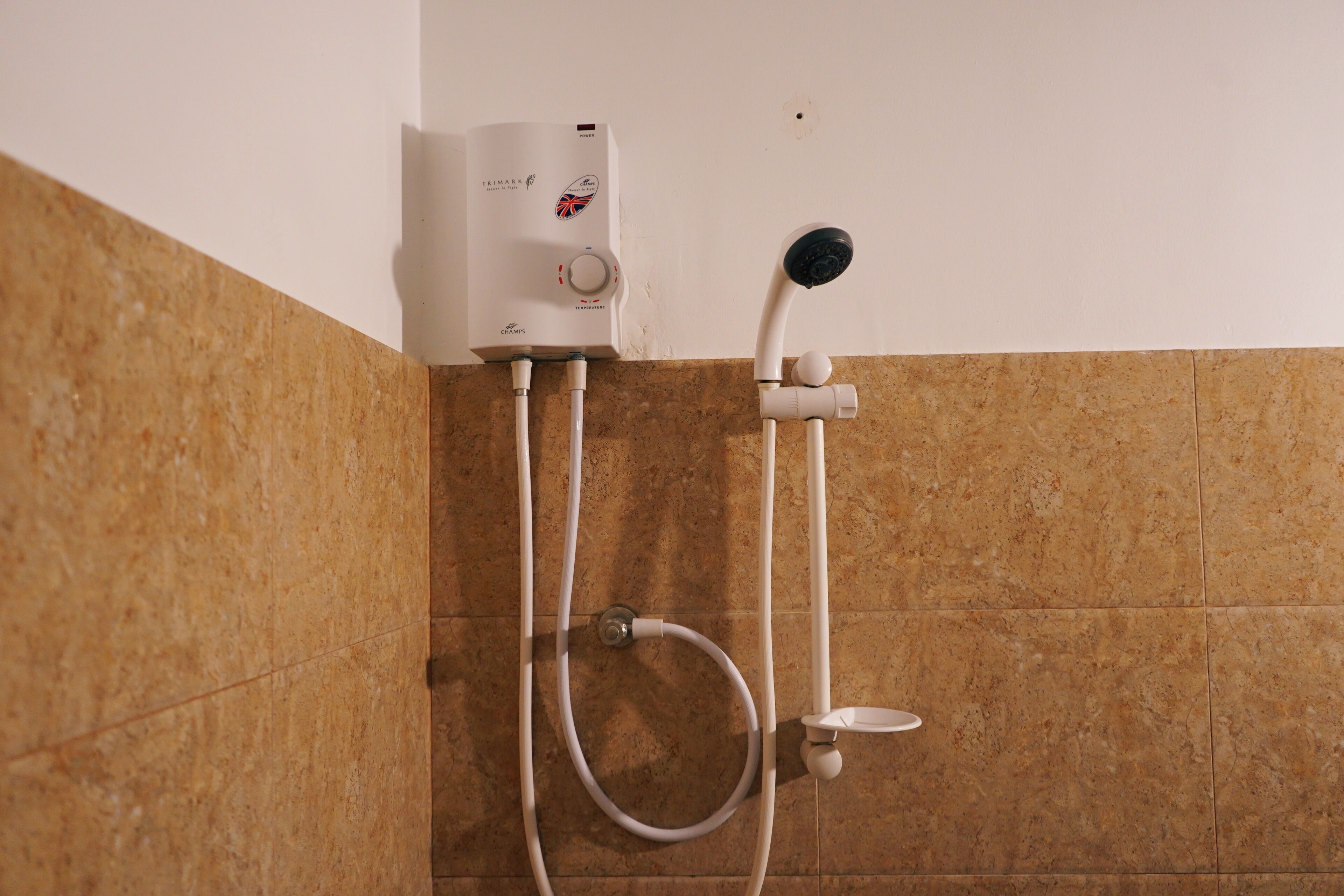 A bathroom with a shower unit, a handheld showerhead, and a wall-mounted control panel.