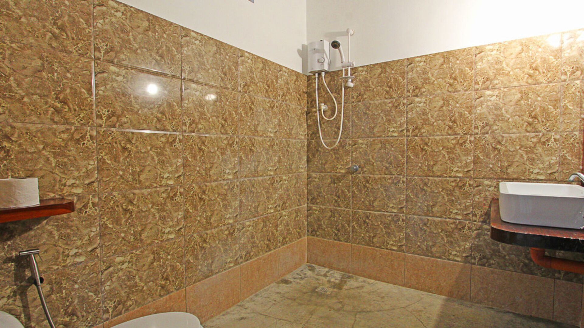 A bathroom with marble walls, a shower, a toilet, and a sink.