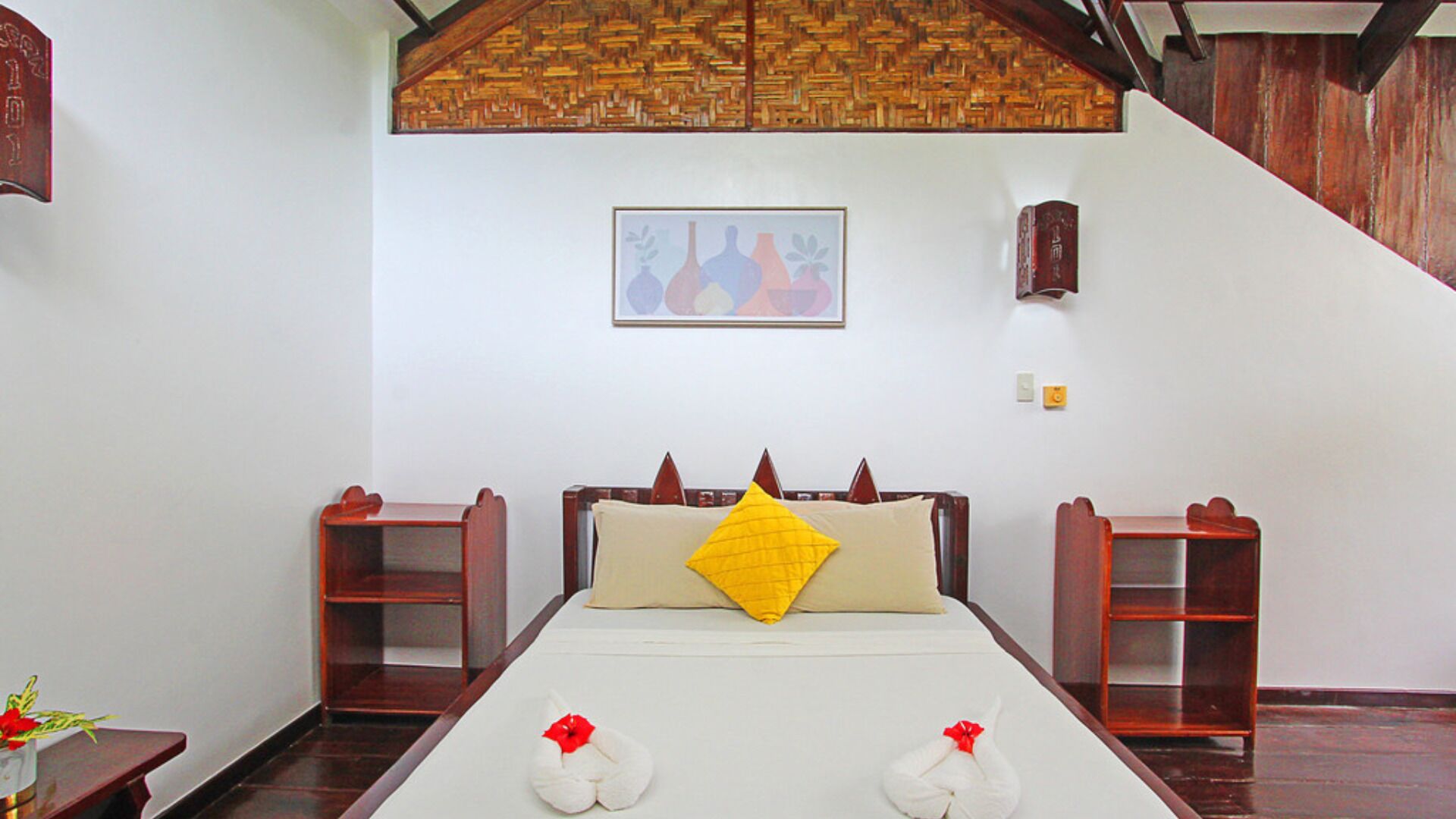 A room with a bed, a wooden headboard, a framed picture on the wall, and a small shelf.