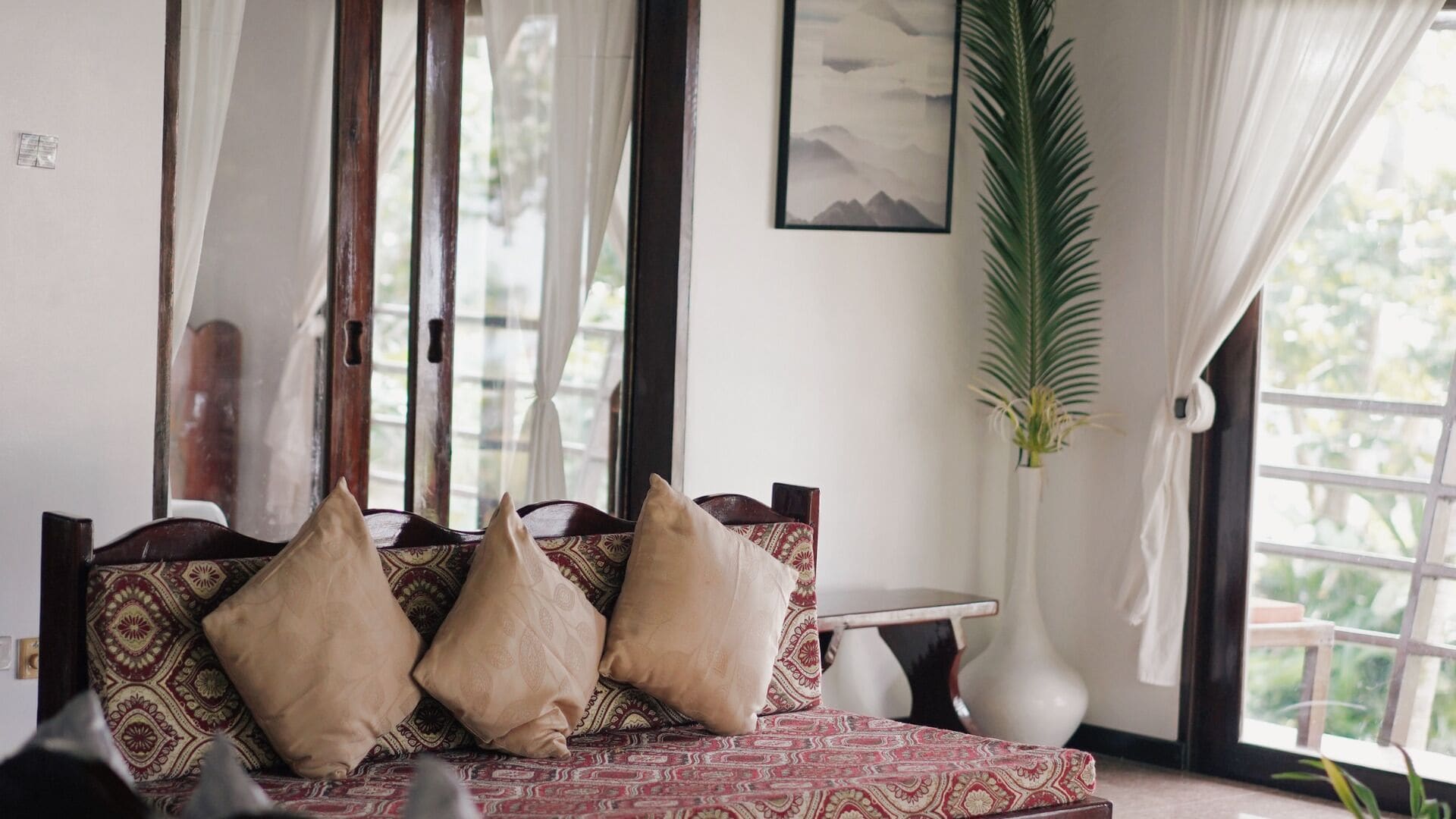 A room with a patterned sofa, a small table, and a large plant.