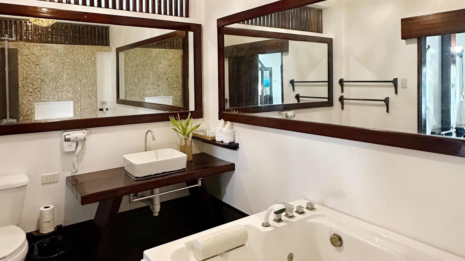 A bathroom with a white sink, two mirrors, a bathtub, and a toilet.