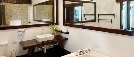 A bathroom with a white sink, two mirrors, a bathtub, and a toilet.