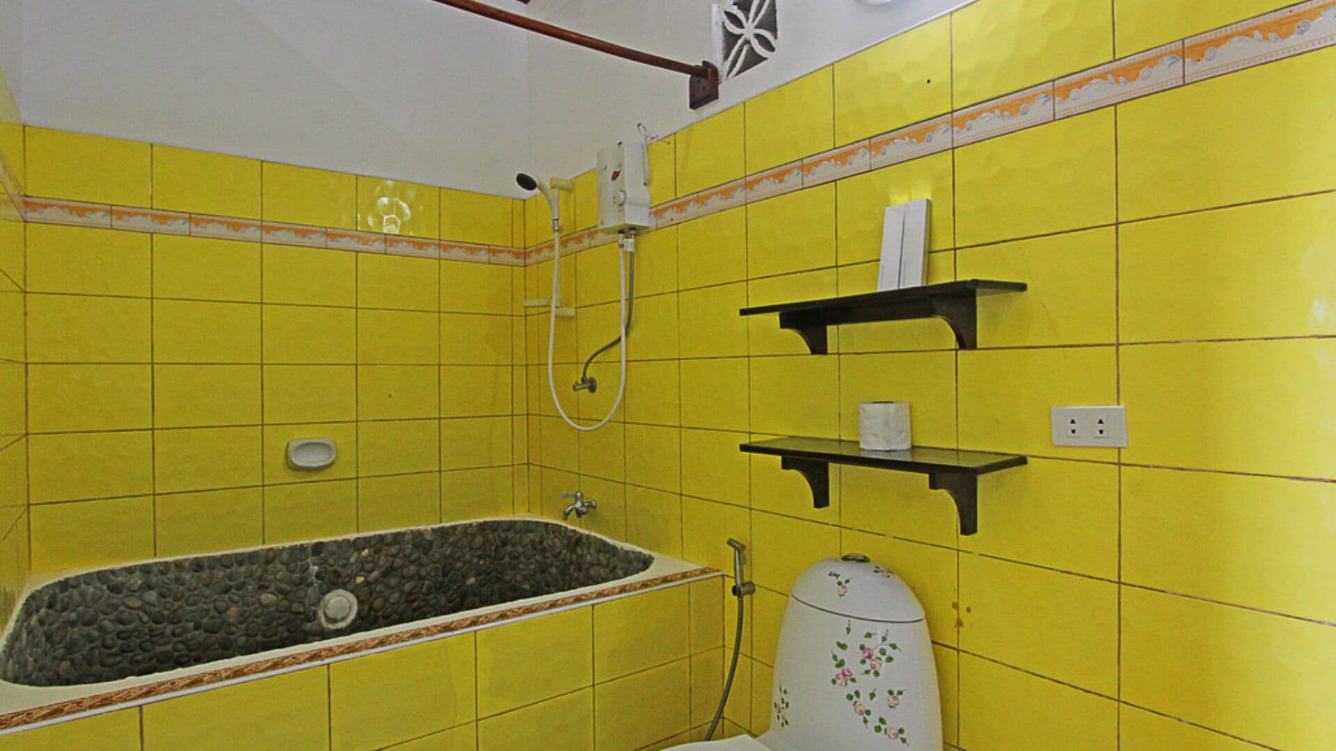 A bathroom with yellow tiles, a bathtub, a toilet, and a shower.