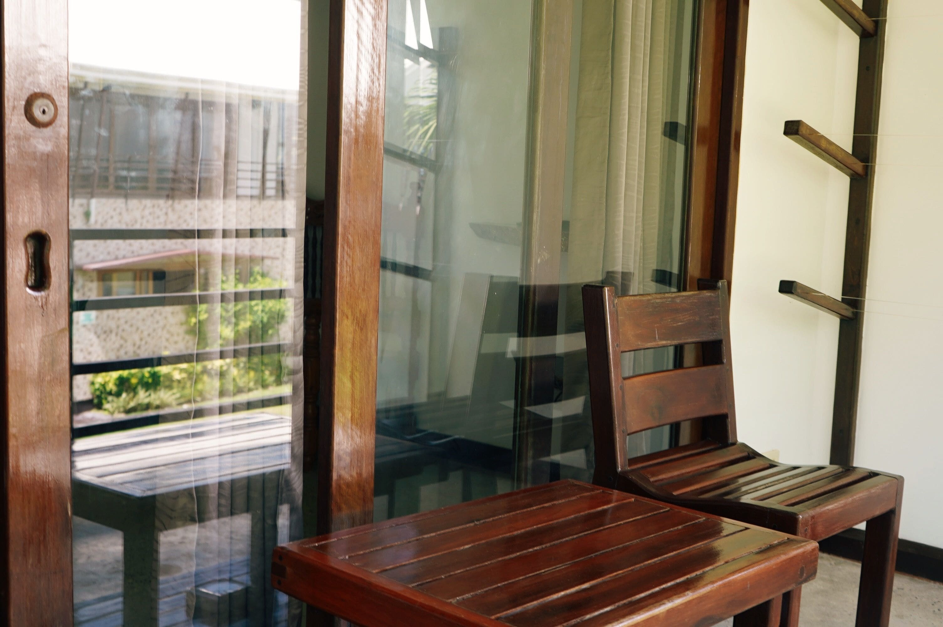 A wooden bench and table in a room with a glass door leading to an outdoor area.