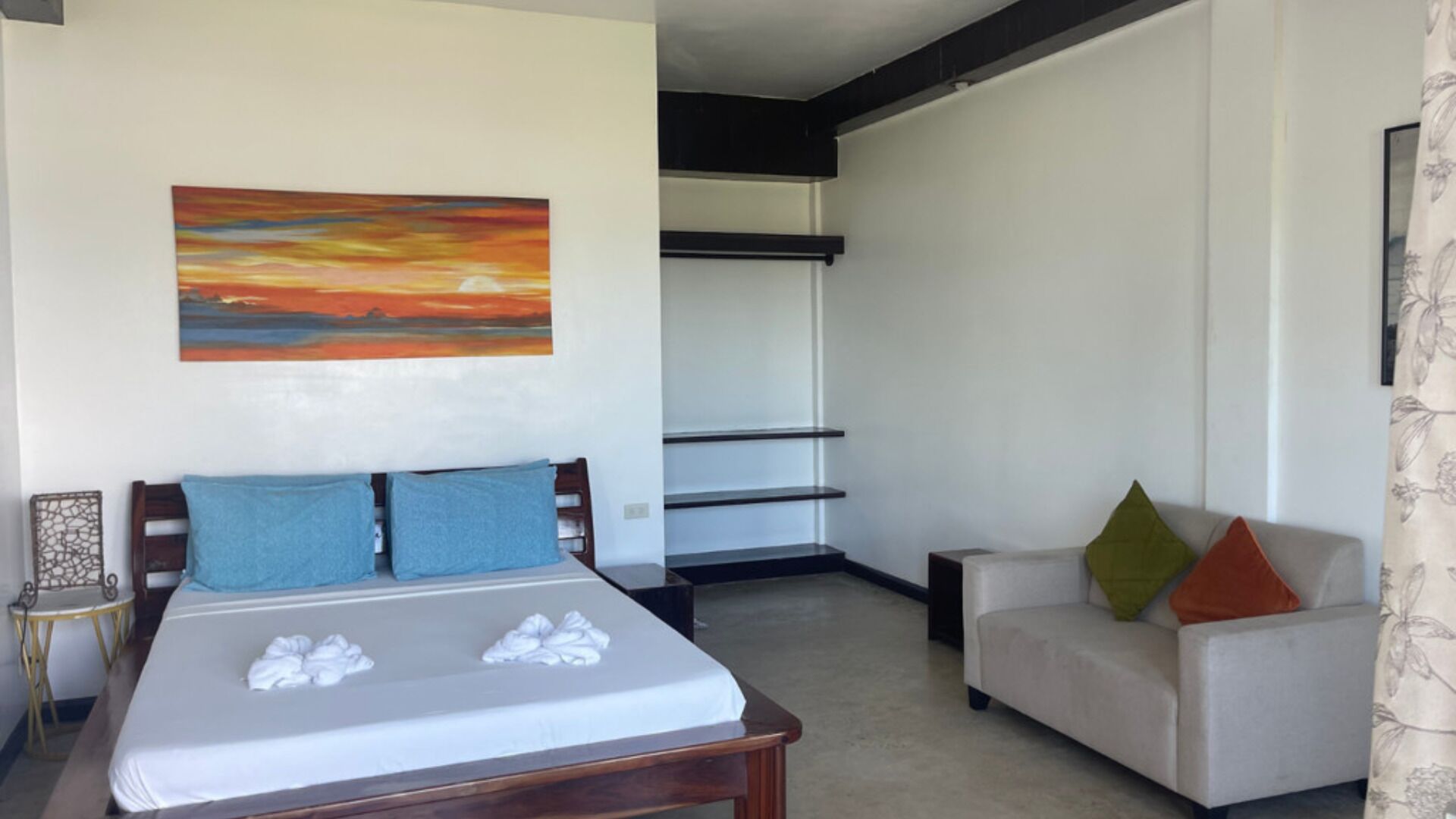 A bedroom with a bed, a chair, a painting, and a wardrobe.