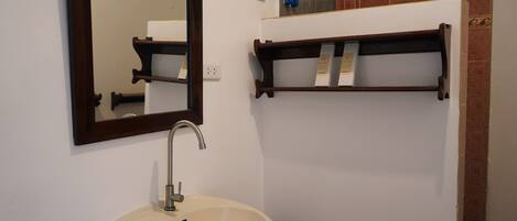 A bathroom with a sink, mirror, and towel rack.