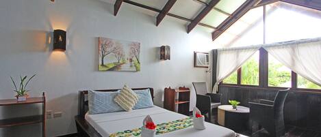 Un dormitorio con una cama, mesitas de noche, un ventanal con cortinas, un aire acondicionado montado en la pared y un cuadro.