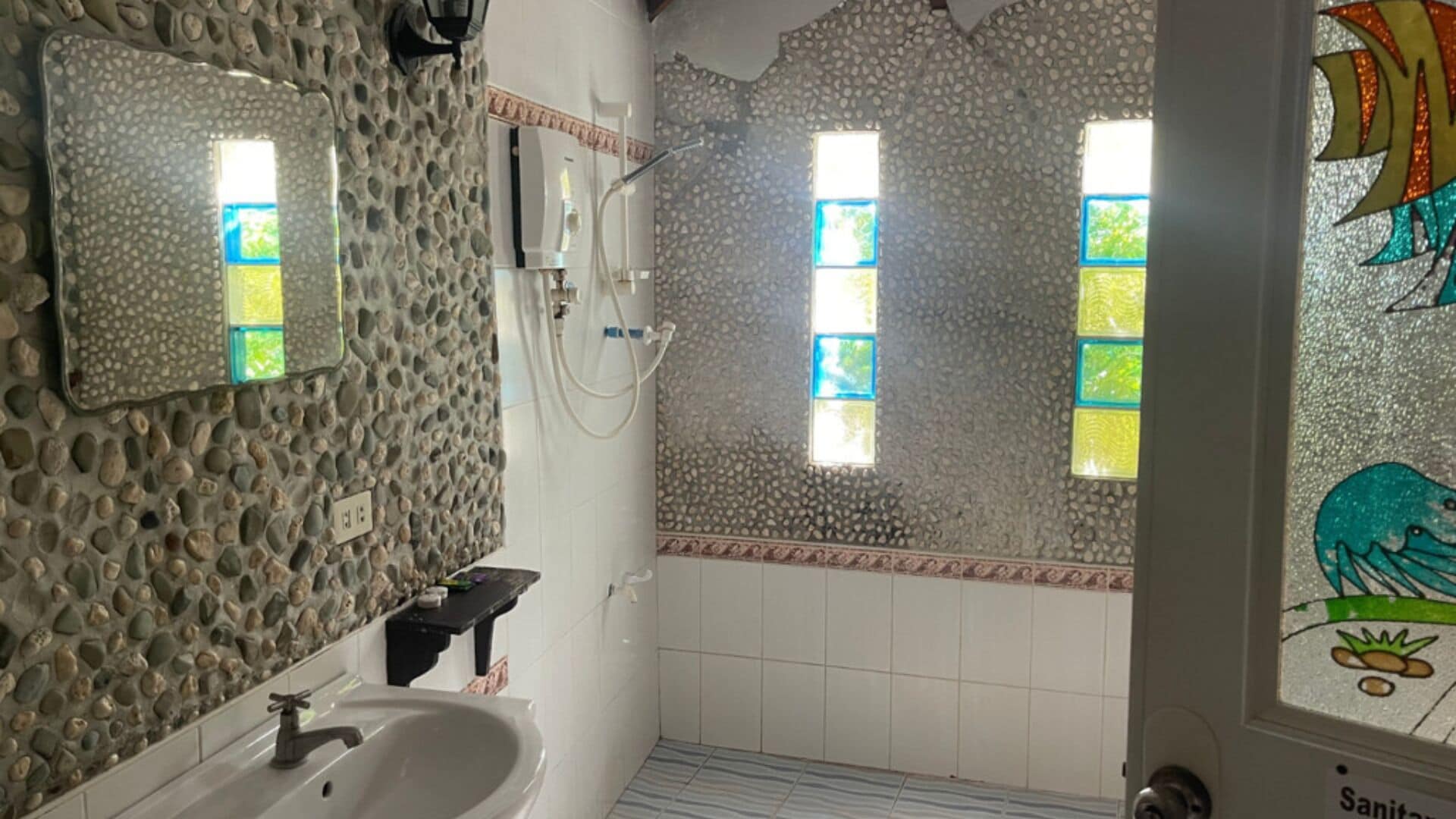 A bathroom with a stone wall, a sink, and a shower area.