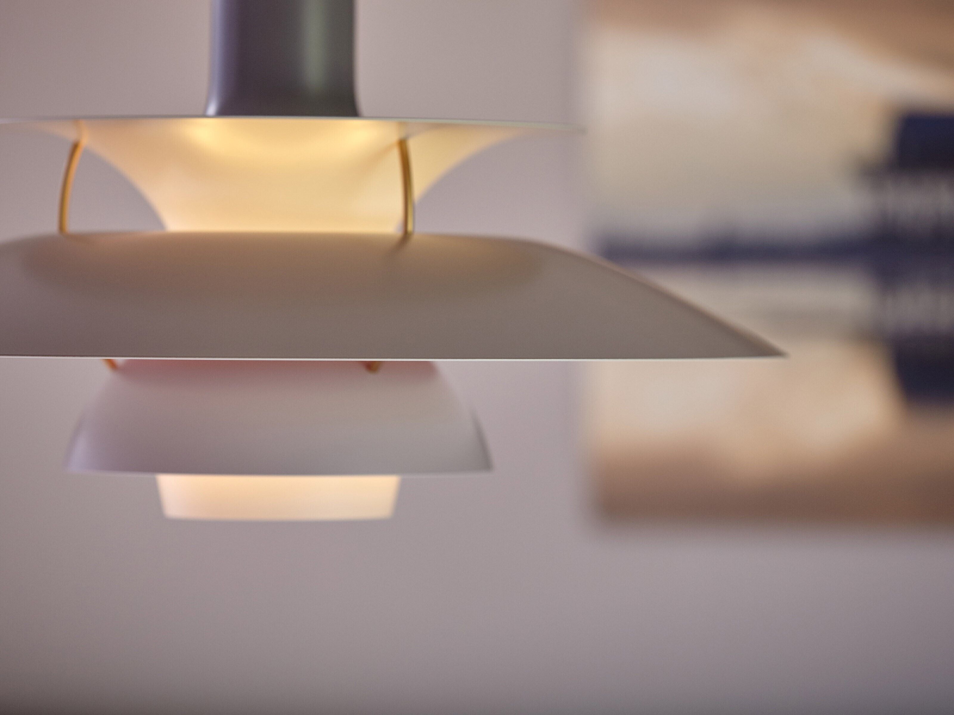 Una lámpara colgante moderna con base metálica y pantalla blanca.