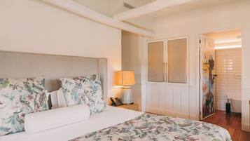 A bedroom with a bed, floral bedding, a nightstand with a lamp, and a wardrobe.
