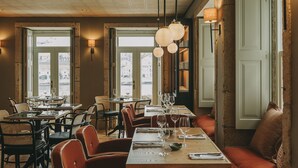 Ein Restaurantinneres mit mehreren Tischen, Stühlen und einer Sitzgruppe mit einer gepolsterten Bank.
