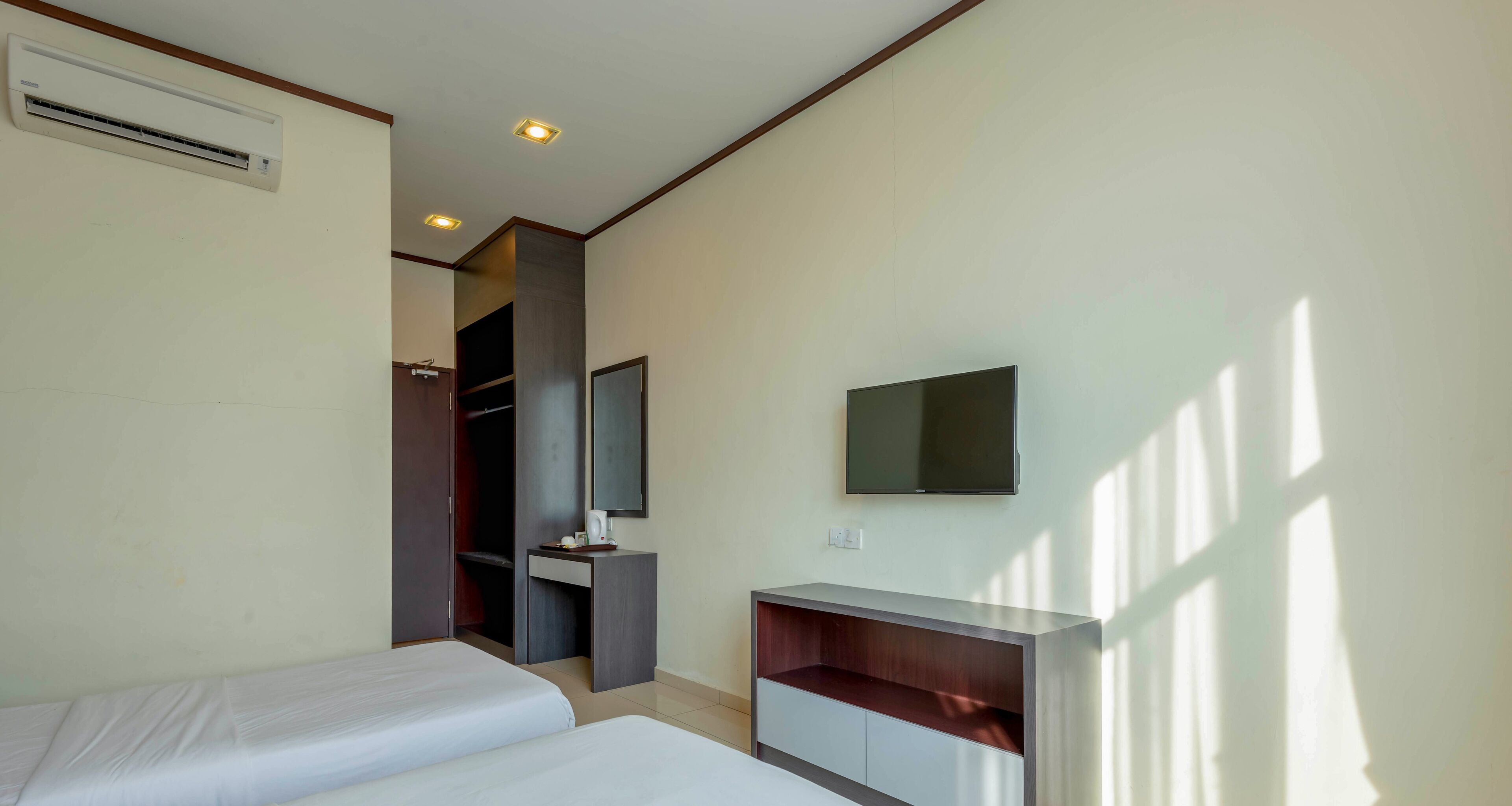 Quarto de hotel com duas camas, uma escrivaninha, televisão e guarda-roupa.