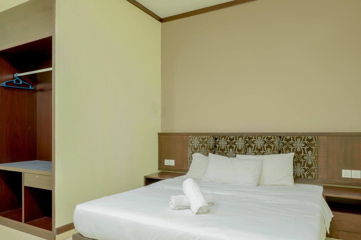 A hotel room with a bed, a wardrobe, and a nightstand.